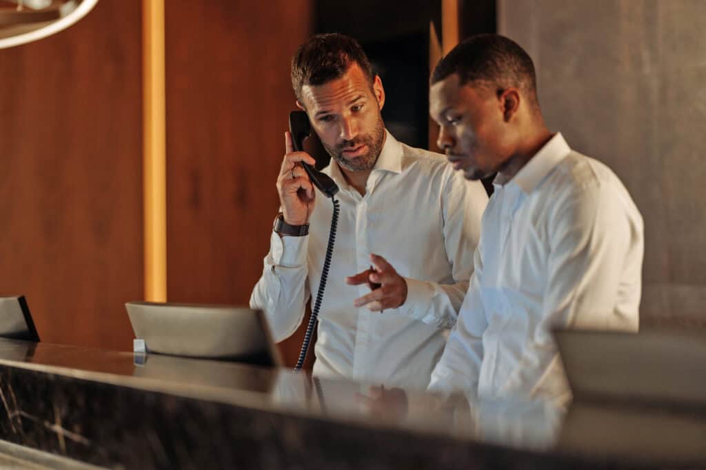 Hotel receptionist engaging in a phone conversation while assisting a customer at the modern front desk